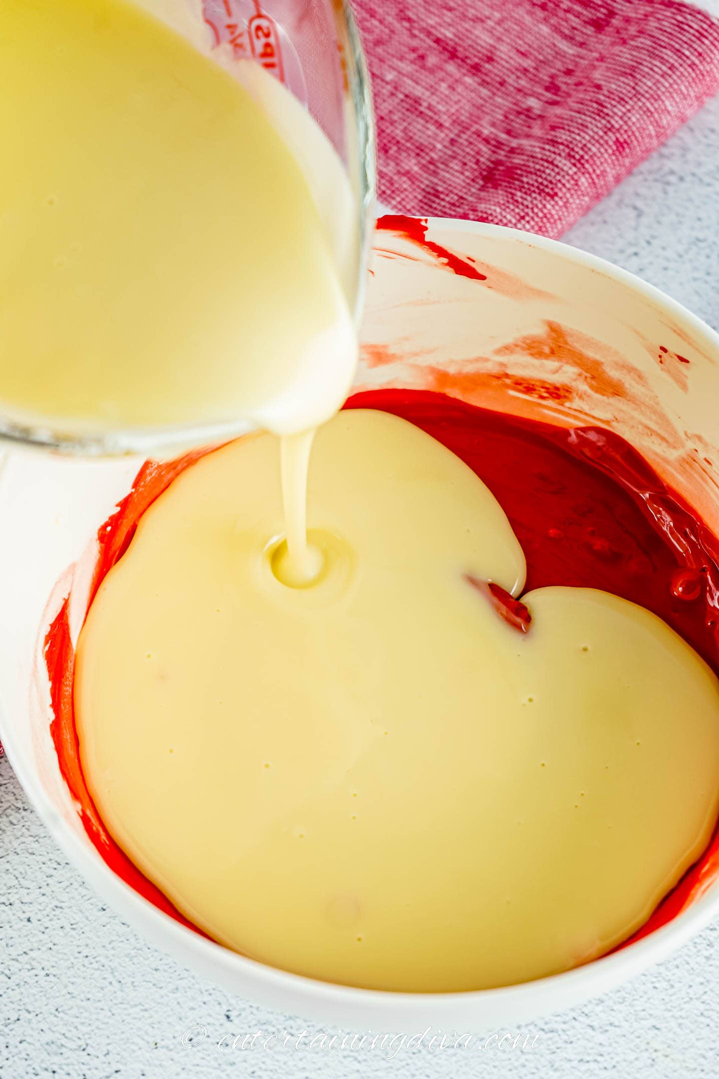 Melted buttercream frosting being poured into red candy chocolate candy melts