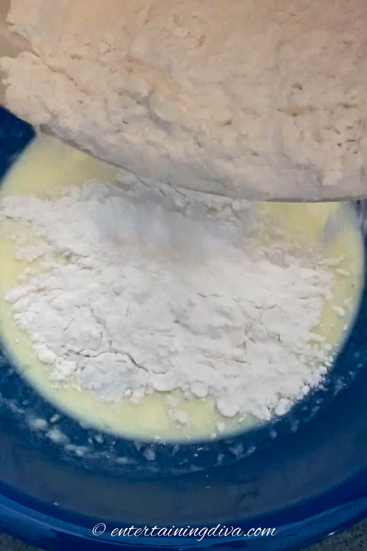 Flour mixture being poured into a bowl with buttermilk mixture
