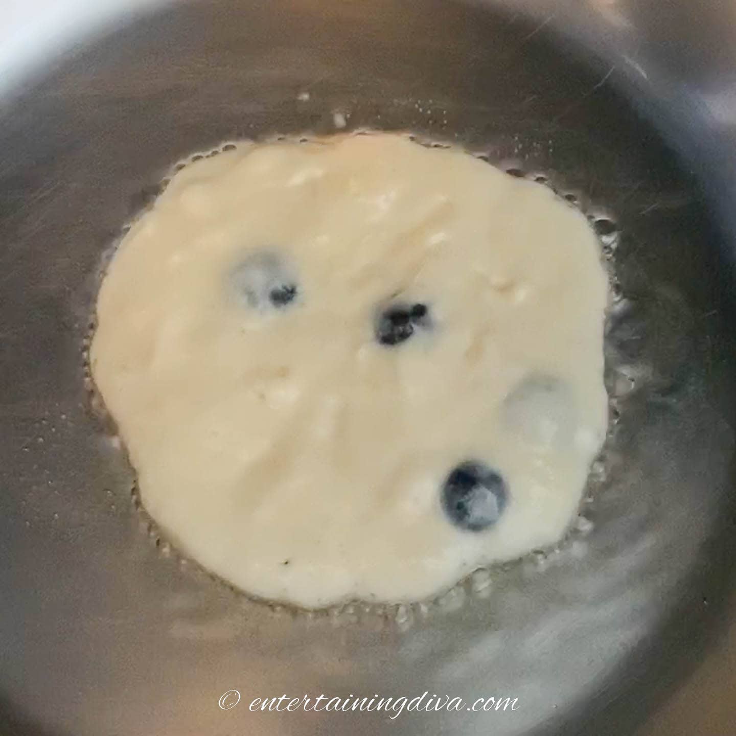 Pancake in the pan with oil sizzling around it