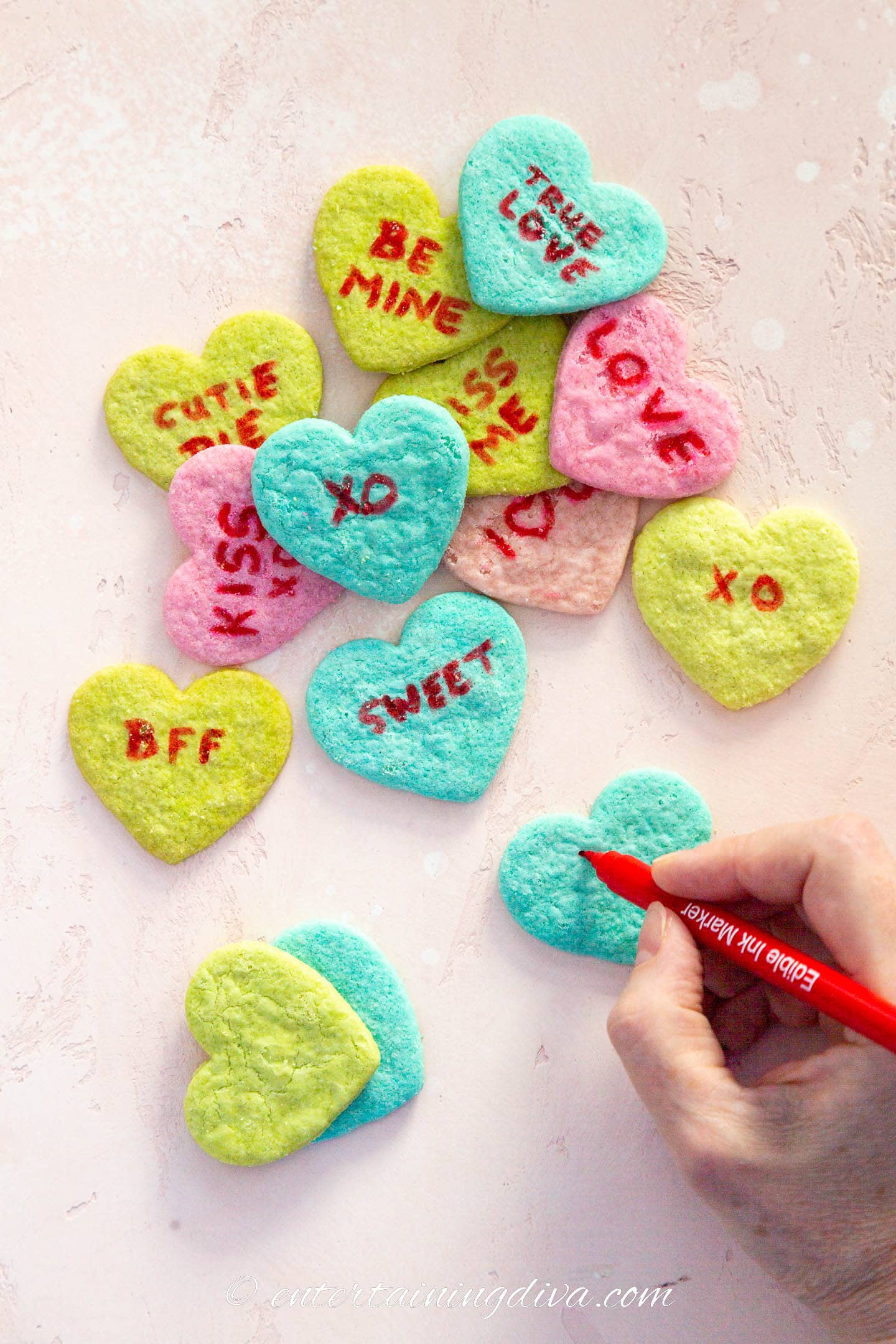 Sayings being written on a blue conversation heart with a red edible ink marker