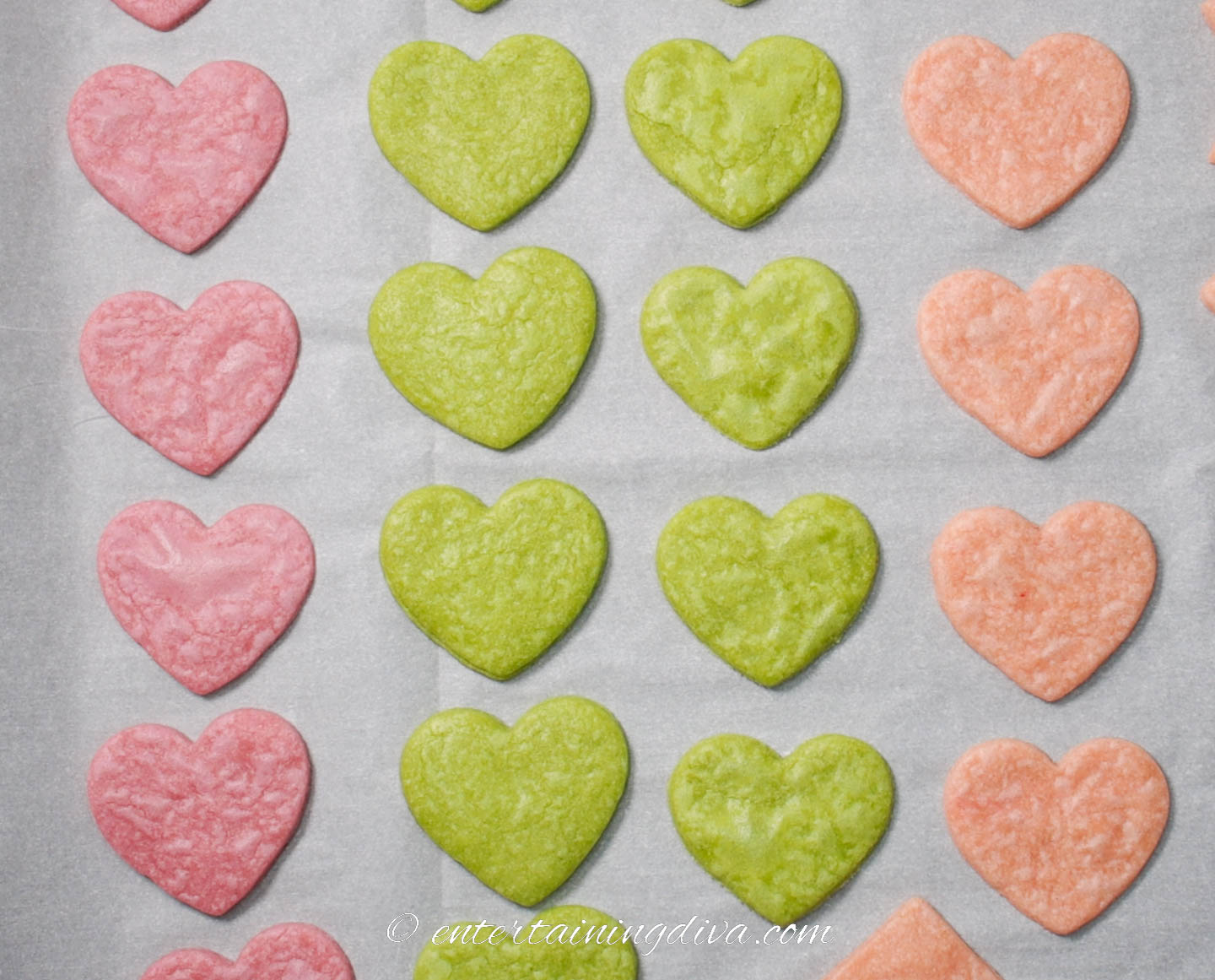 red, green and pink heart cookies on a baking sheet