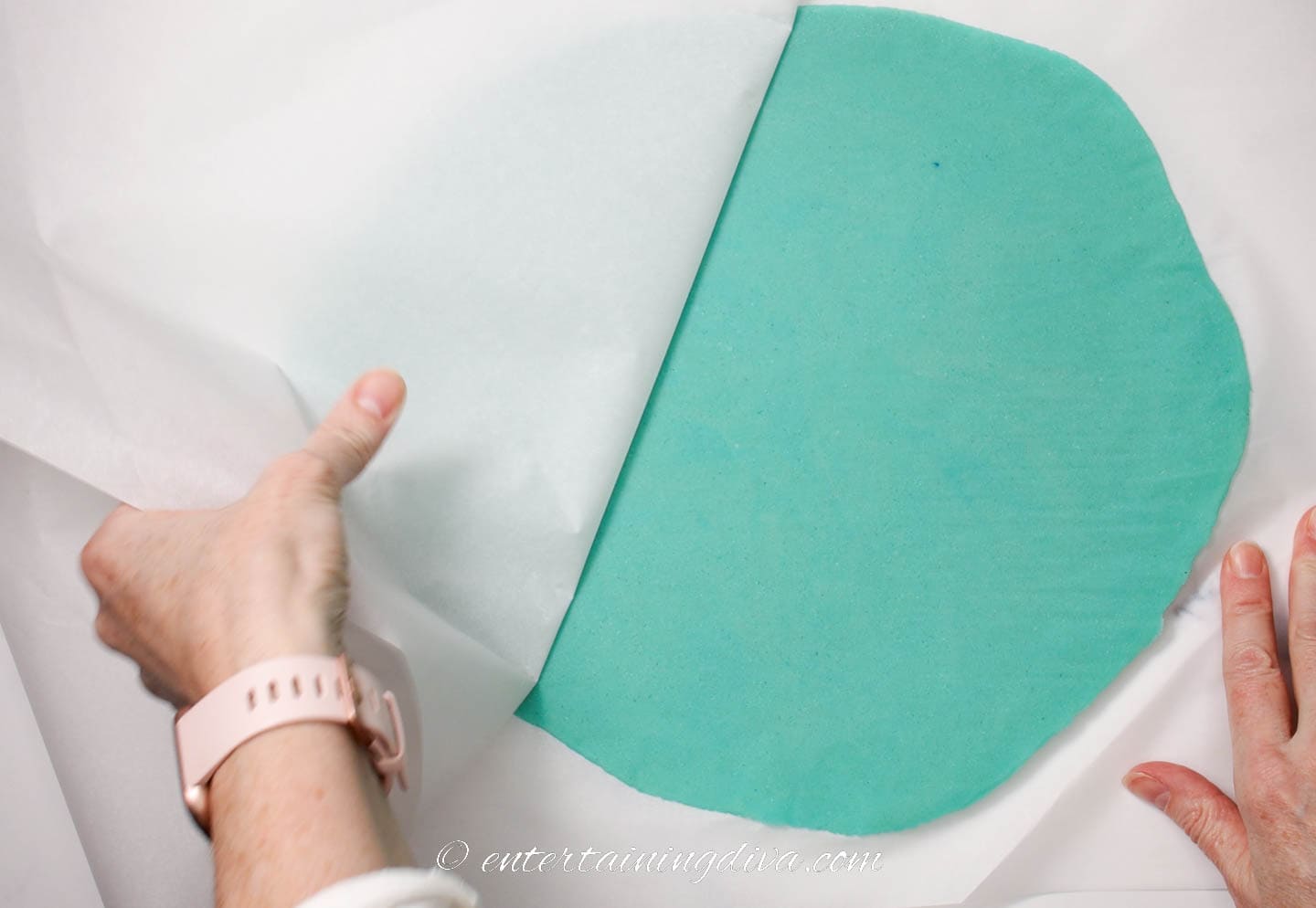 Parchment paper being removed from the rolled out blue cookie dough