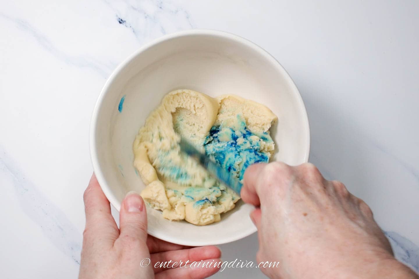 Blue food coloring being added to cookie dough