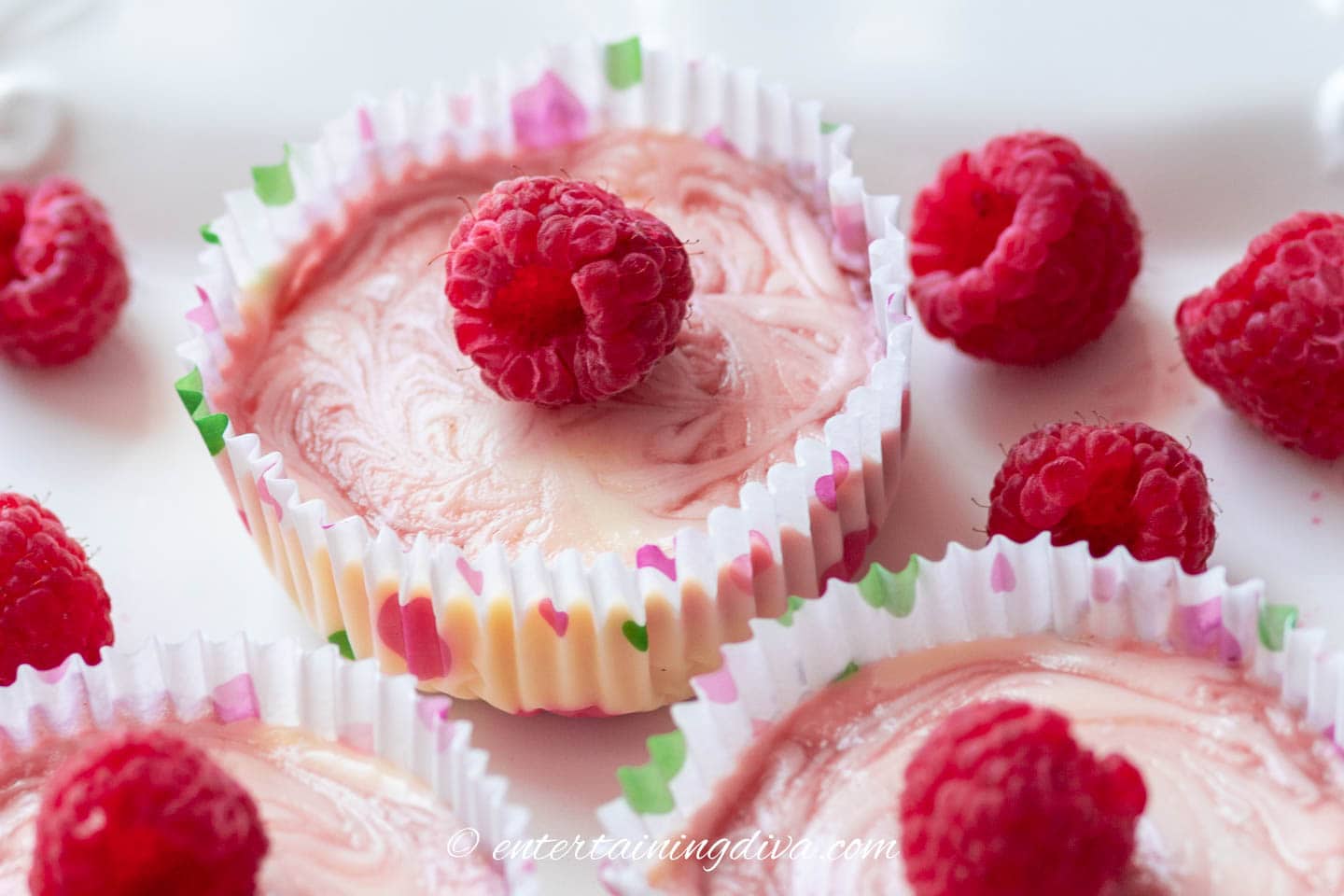 close up of a raspberry swirl mini cheesecake with fresh raspberries