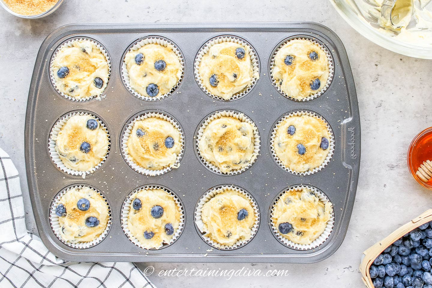 Turbinado sugar on top of blueberry muffins in a muffin tin.