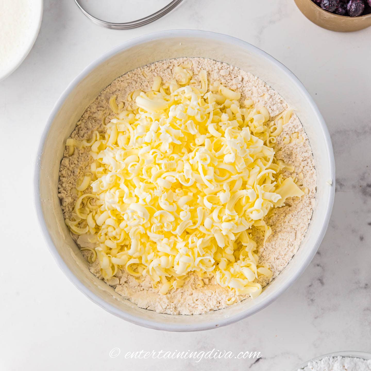grated frozen butter in a bowl with the flour mixture