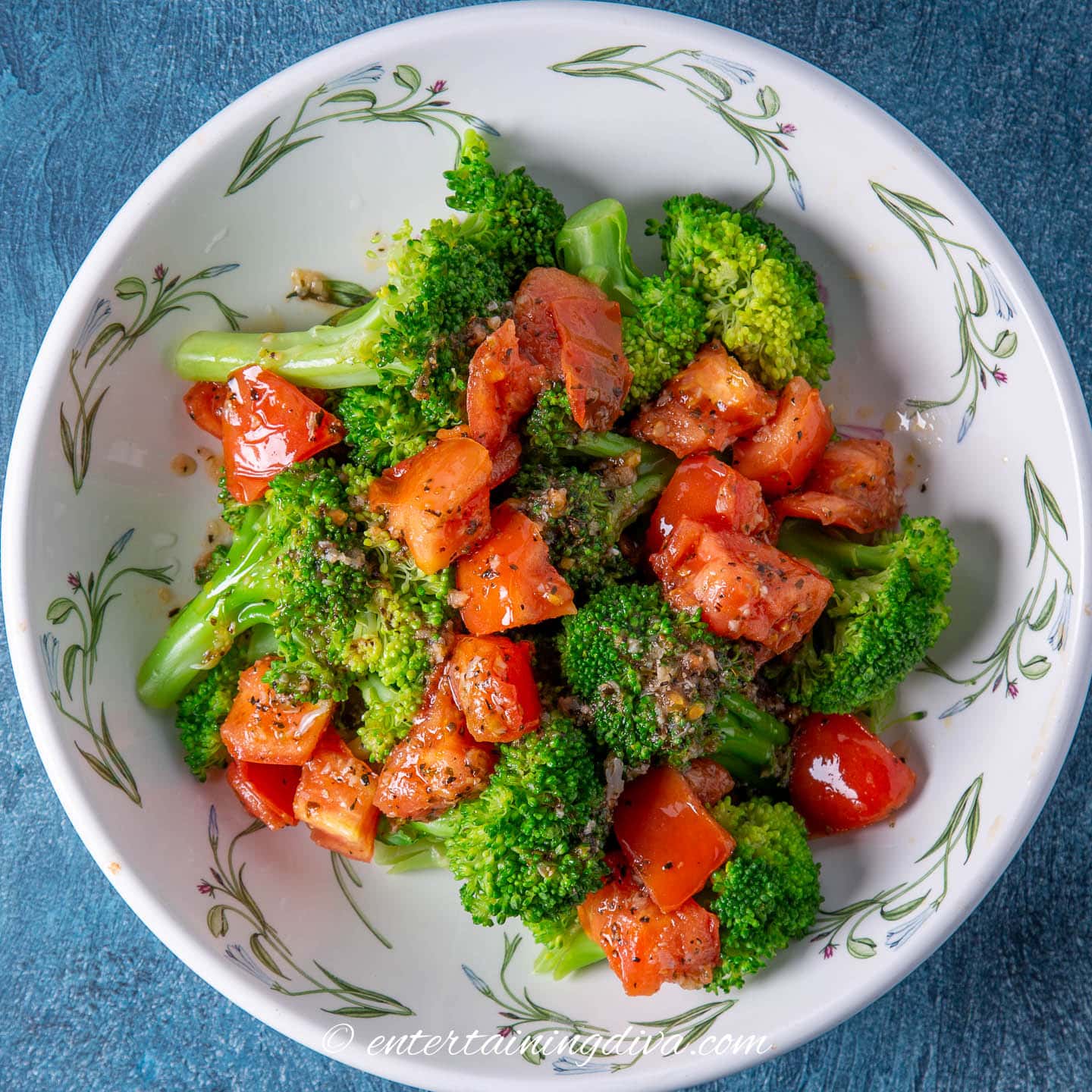 Overhead view of microwaved broccoli with tomatoes and spices in a serving bowl