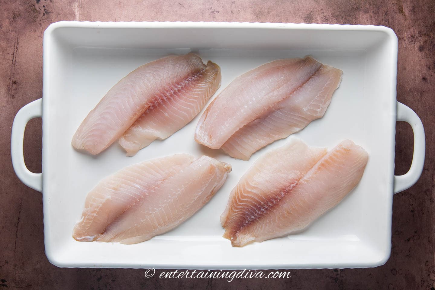 4 tilapia fillets in a baking dish