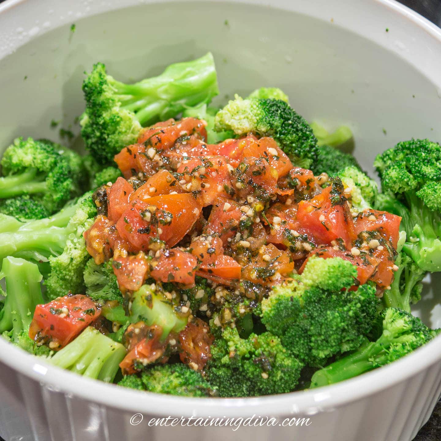 Tomato mixture on top of microwaved broccoli in a glass baking dish