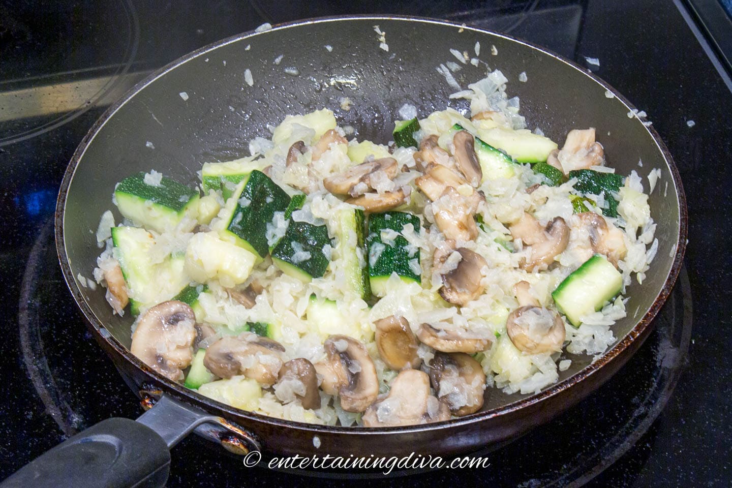 zucchini, mushrooms and onions in a saute pan
