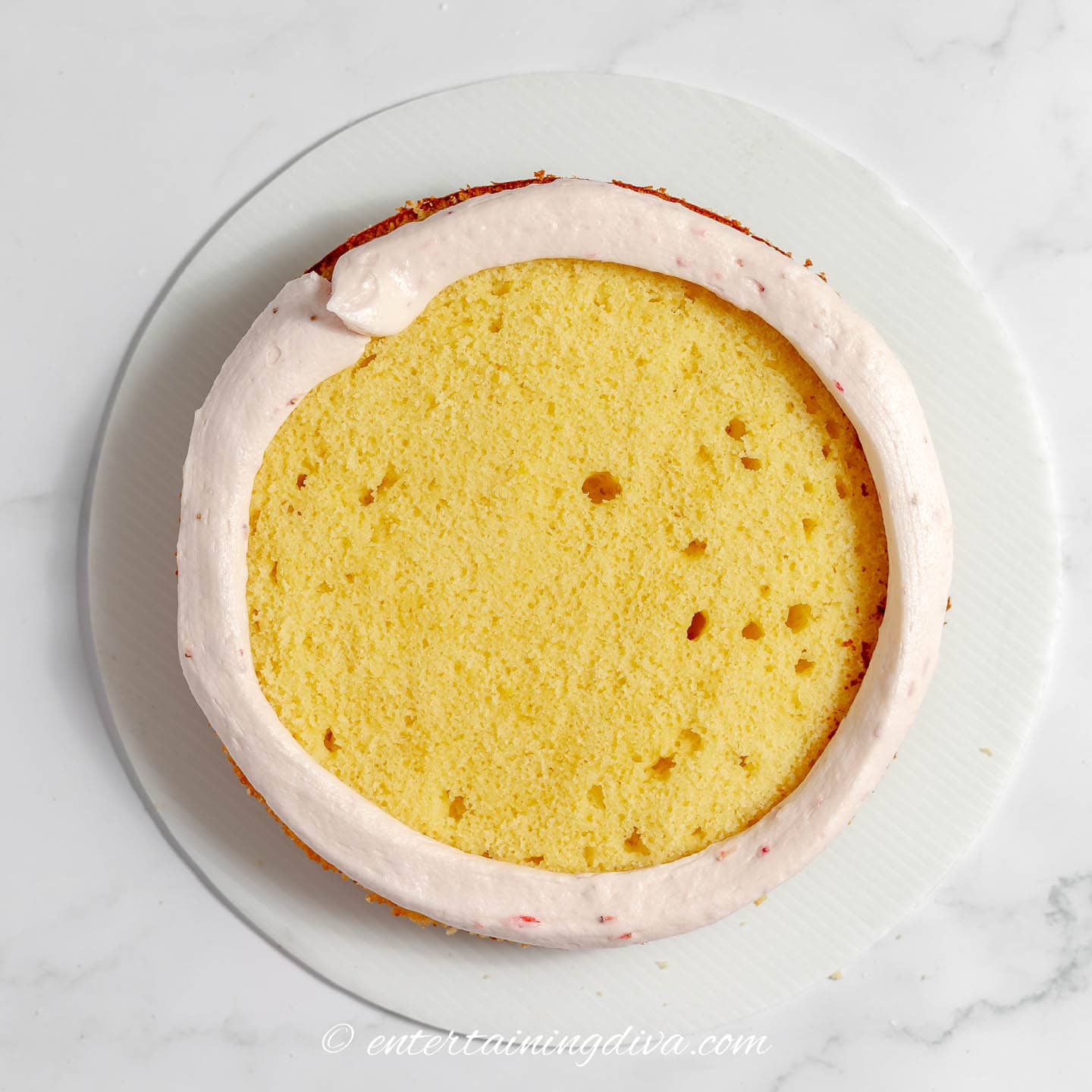 layer of lemon cake with strawberry frosting around the edge