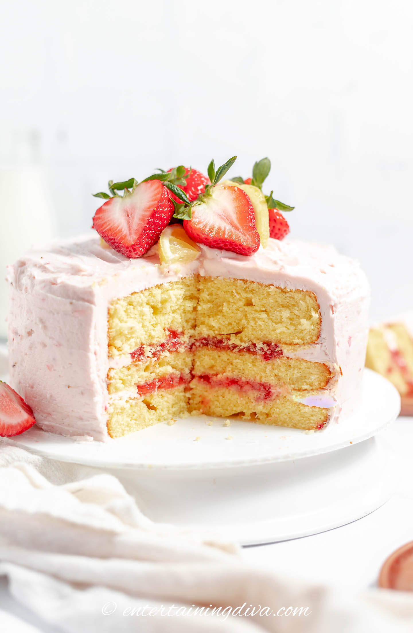 Side view of a strawberry lemon cake with a piece cut out of it