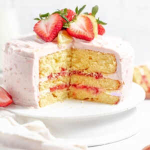 strawberry lemon cake with a piece cut out of it and strawberries on top
