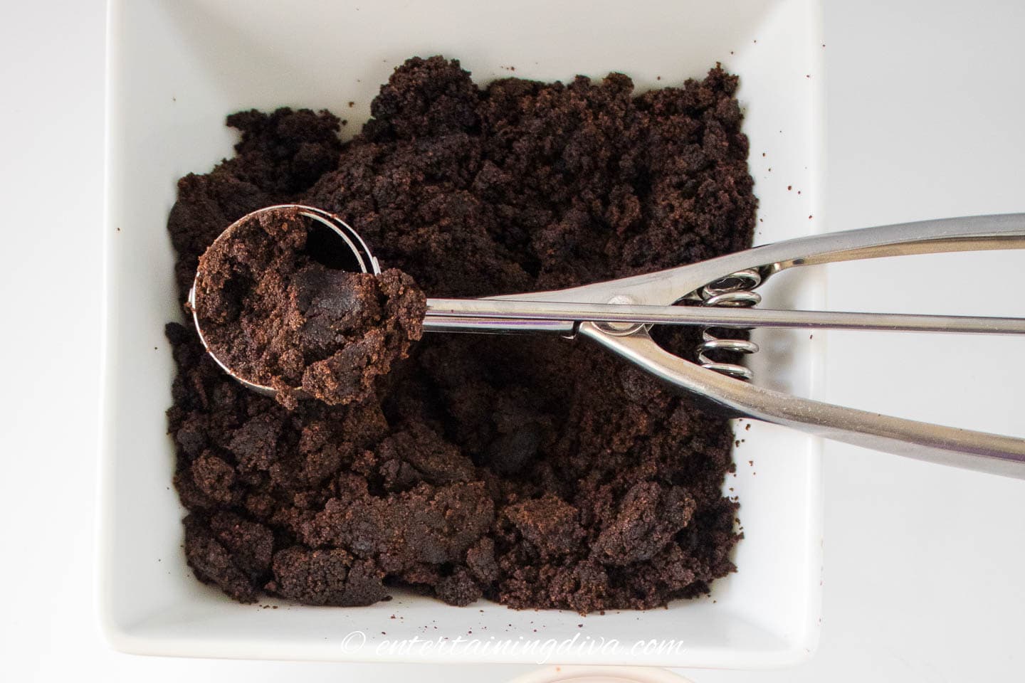 chocolate cake pop dough in a bowl with a cookie scoop
