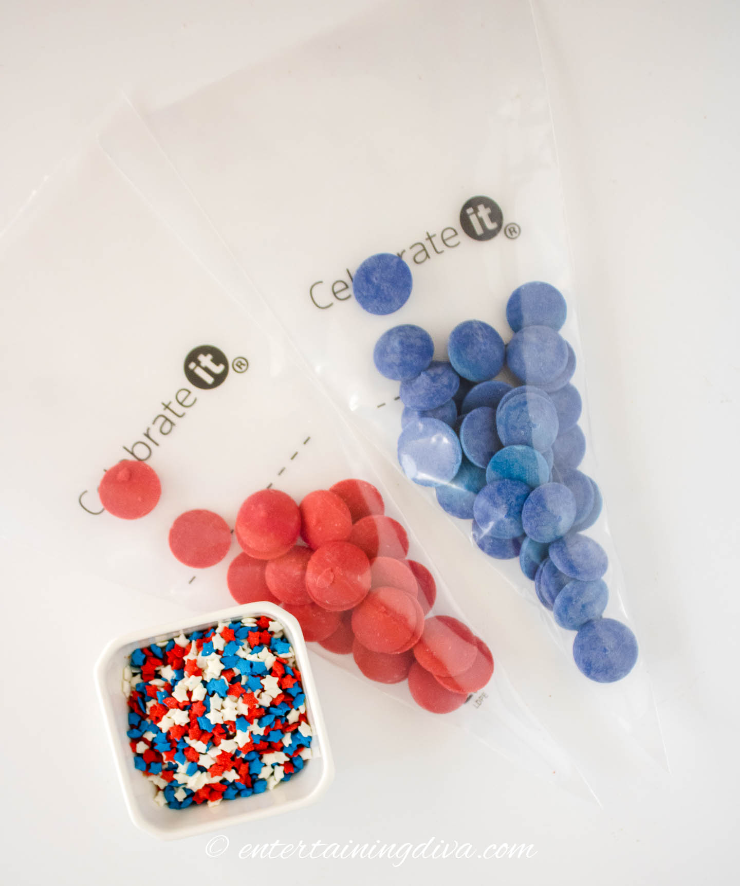 Red and blue candy melts in piping bags beside a bowl of star sprinkles