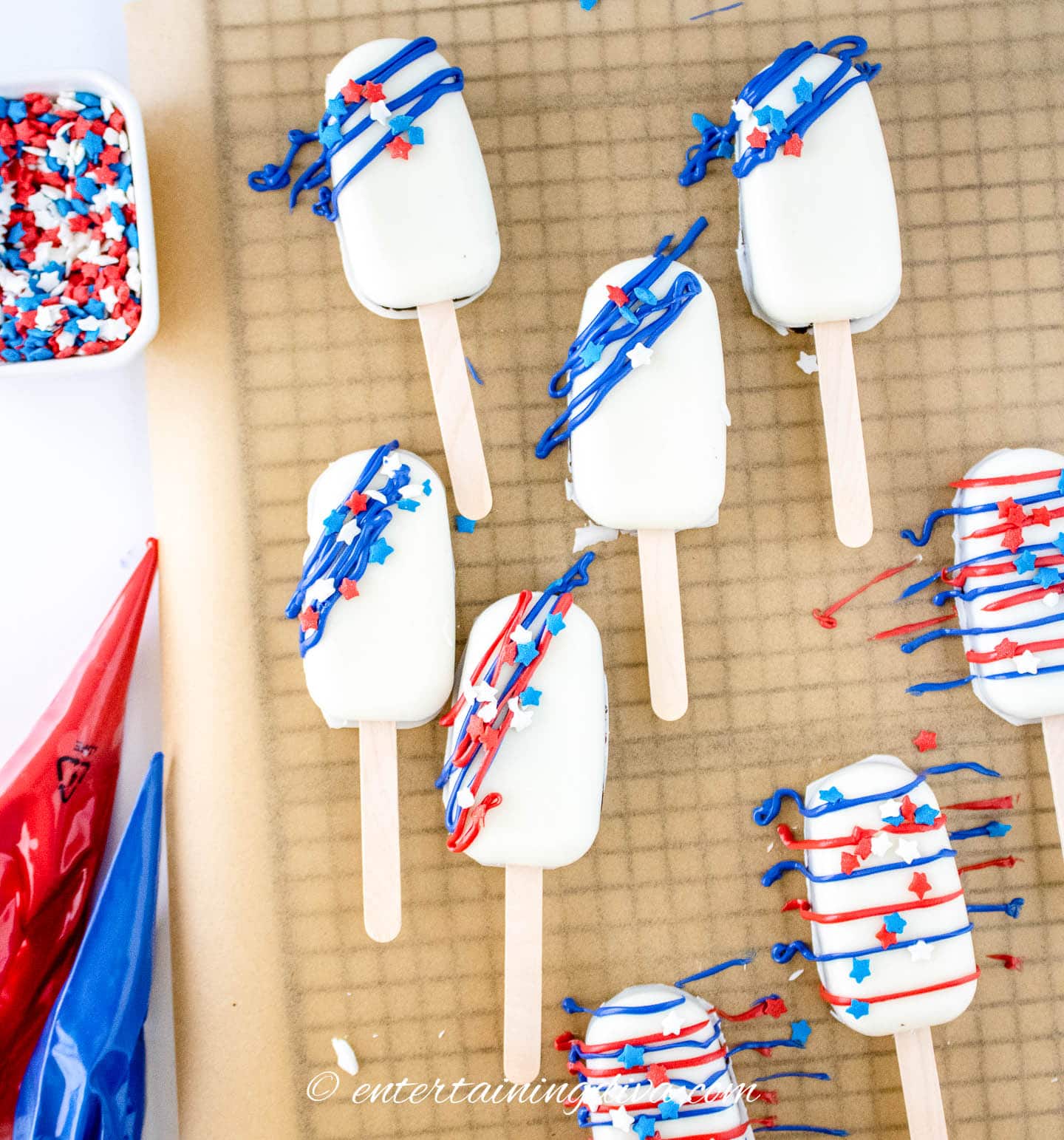 White cakesicles decorated with red and blue icing and star sprinkles