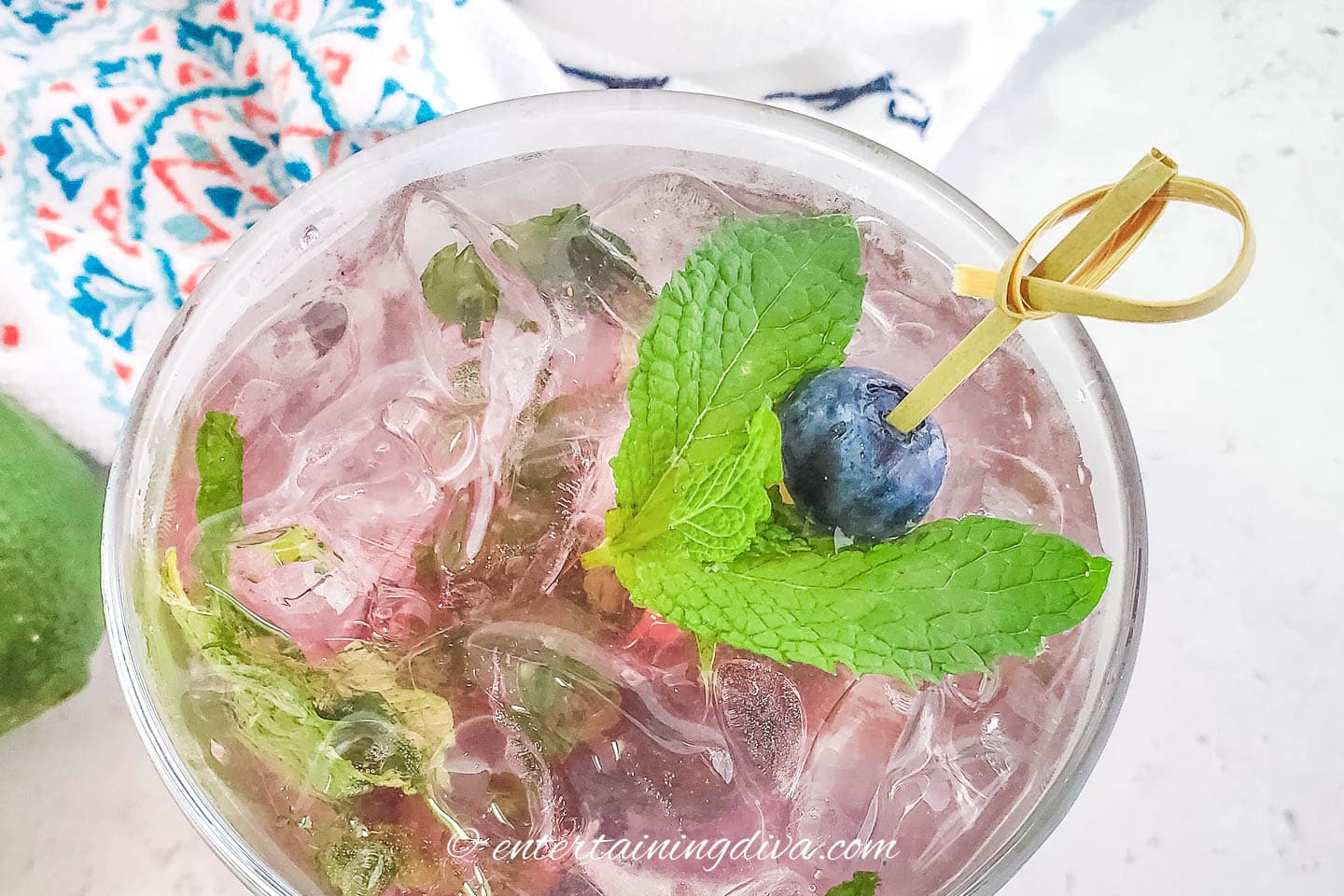 Mint leaves and a blueberry garnish on top of a blueberry mojito