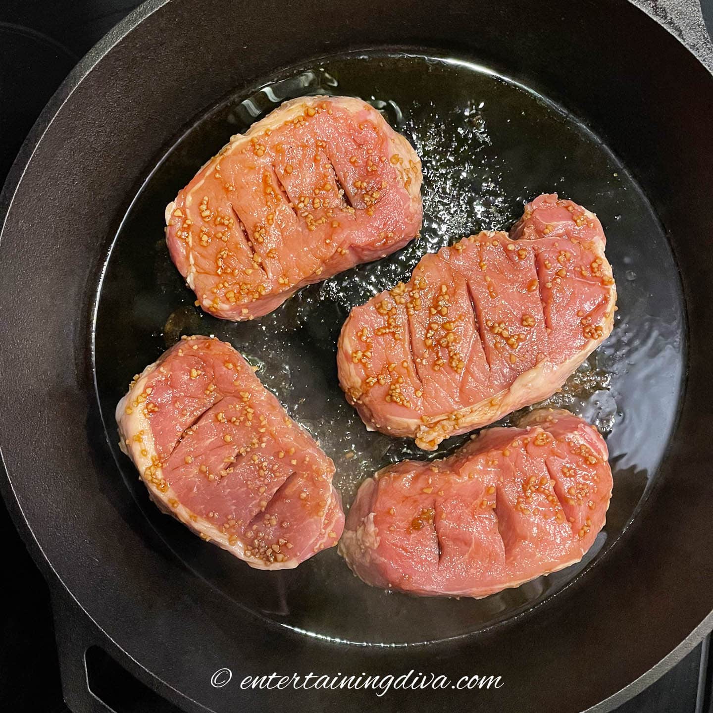 Thick pork chops being seared in a frying pan