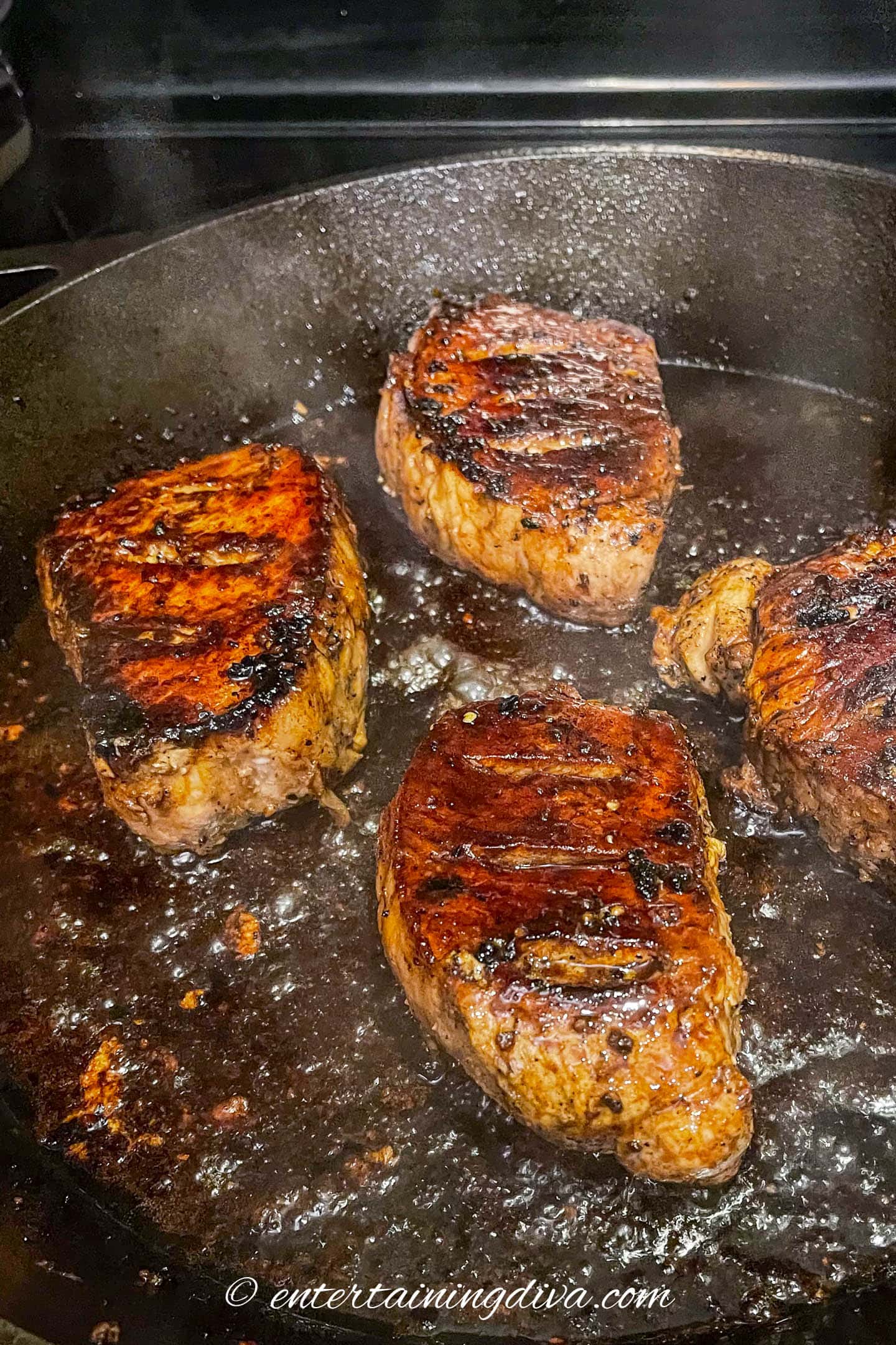 Thick pork chops covered in marinade in a frying pan