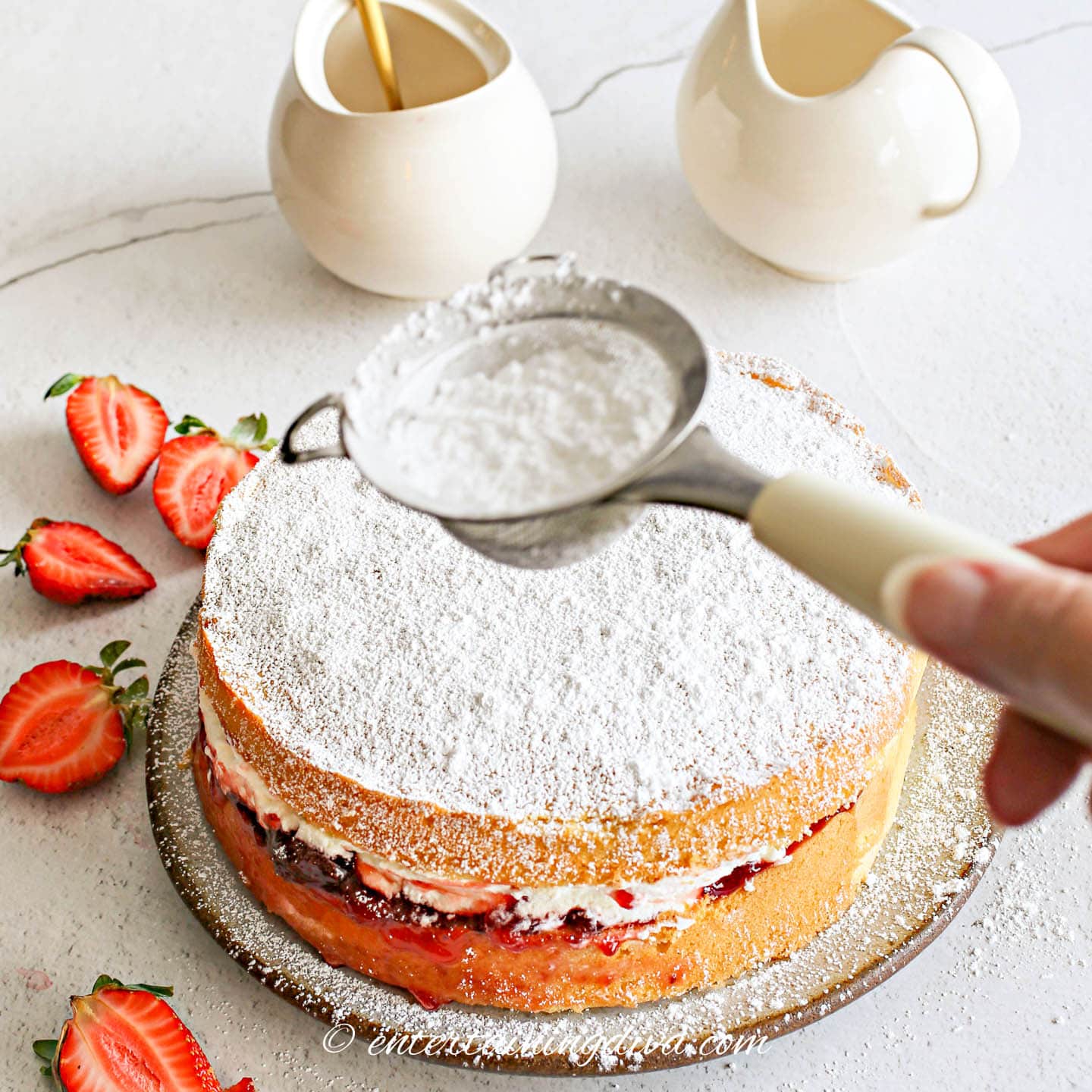 Sprinkling powdered sugar on top of strawberry shortcake cake