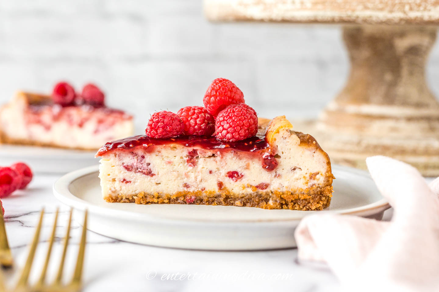 Side view of a slice of baked raspberry cheesecake on a plate