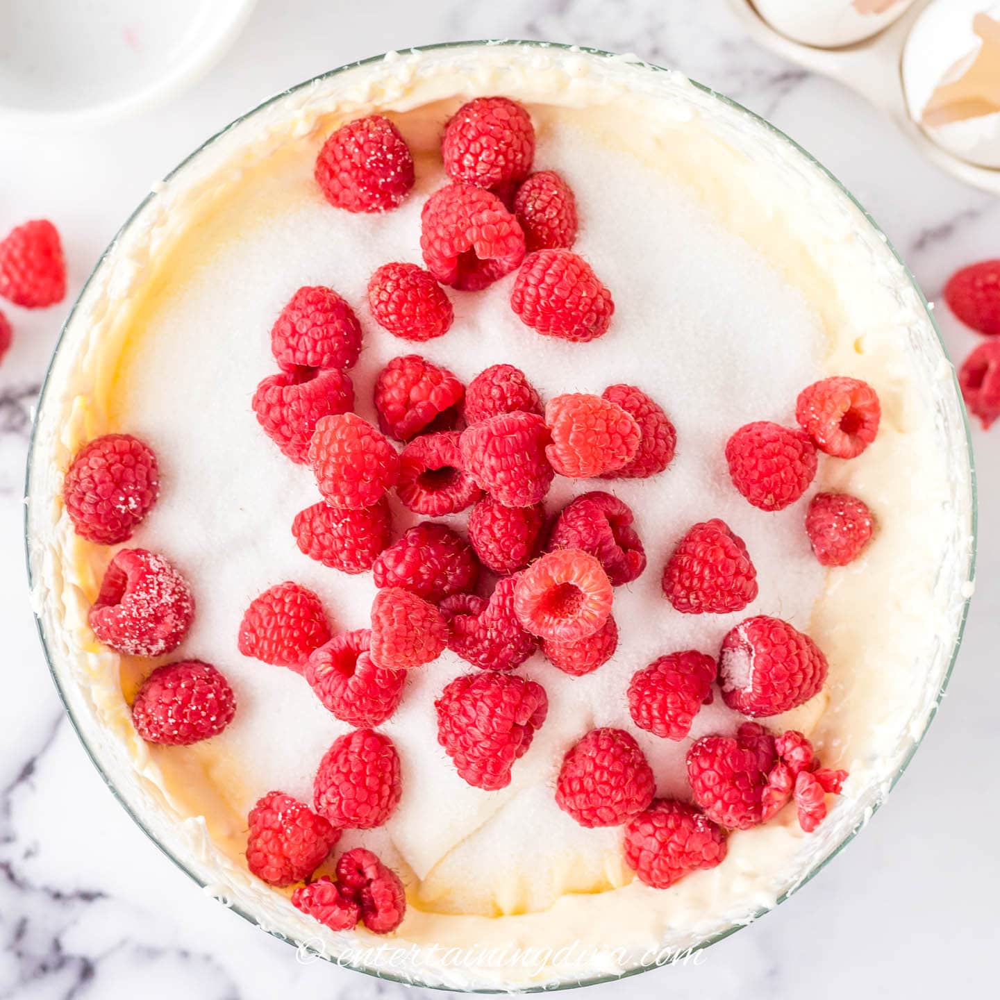 fresh raspberries on top of a bowl of  cheesecake batter