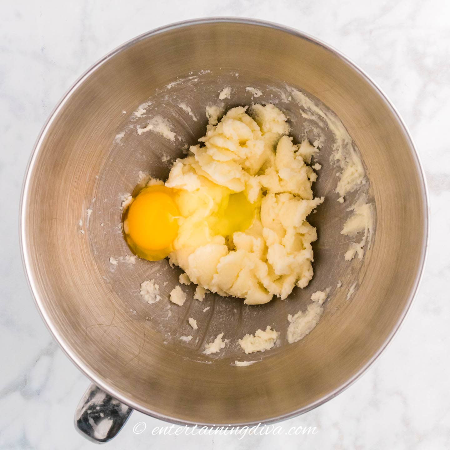 egg on top of butter and sugar mixture in a bowl