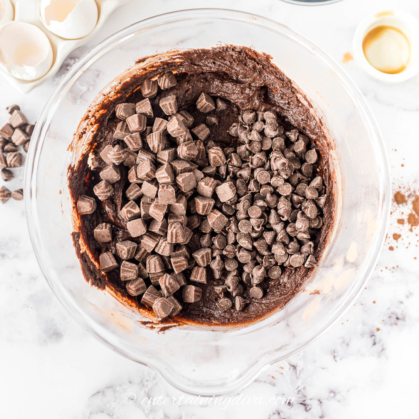 Chocolate chips and caramel dulce de leche truffles on top of the brownie batter in a bowl