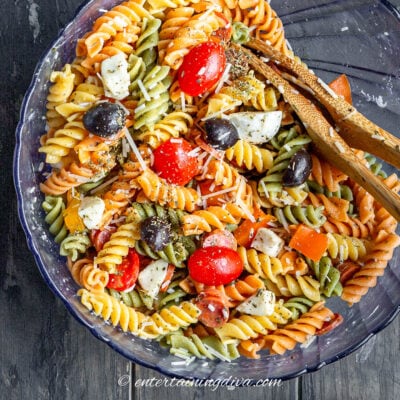Close up of Italian pasta salad in a bowl with serving spoons