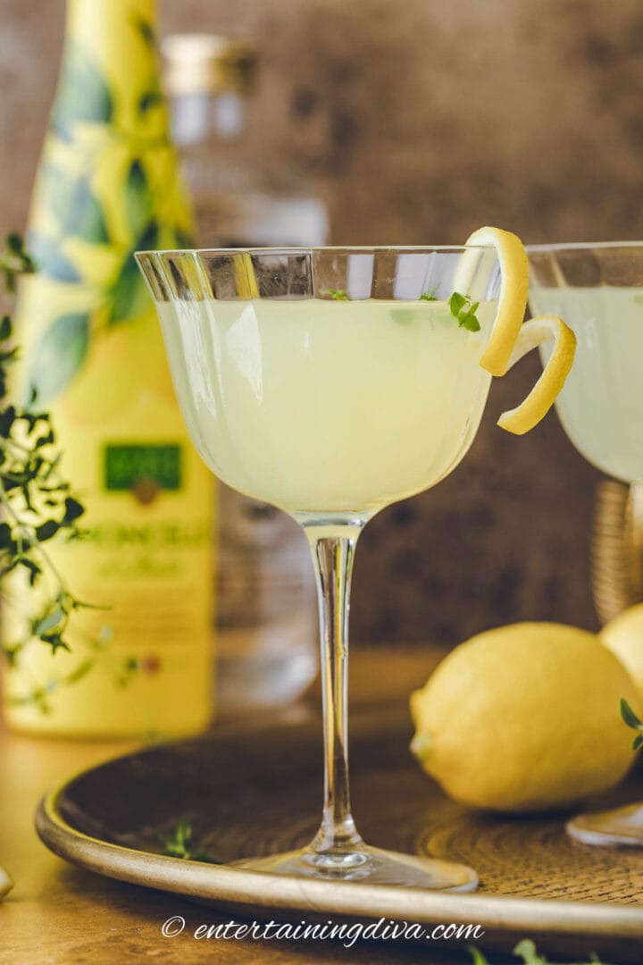 Lemon drop martini made with limoncello on a tray with a bottle of limoncello.