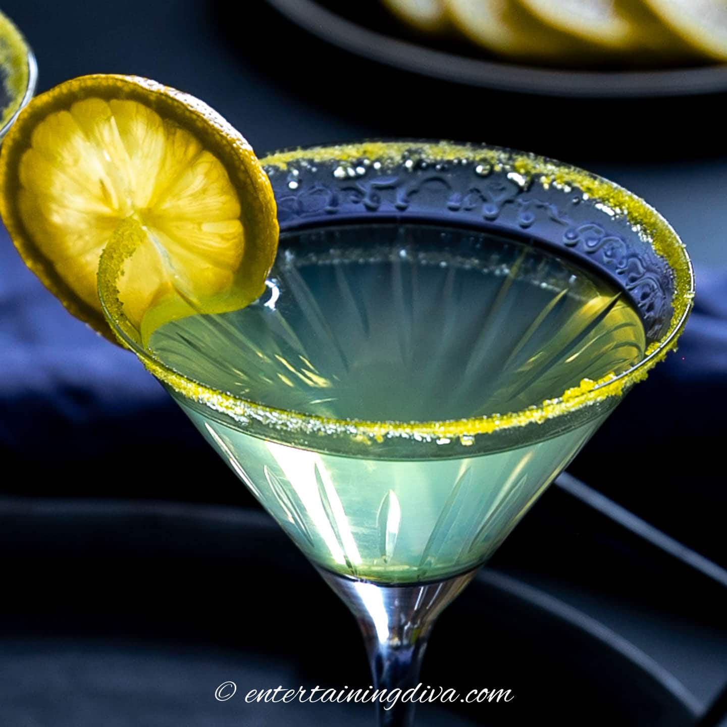 A limoncello martini with a rimmed glass and a slice of lemon garnish.