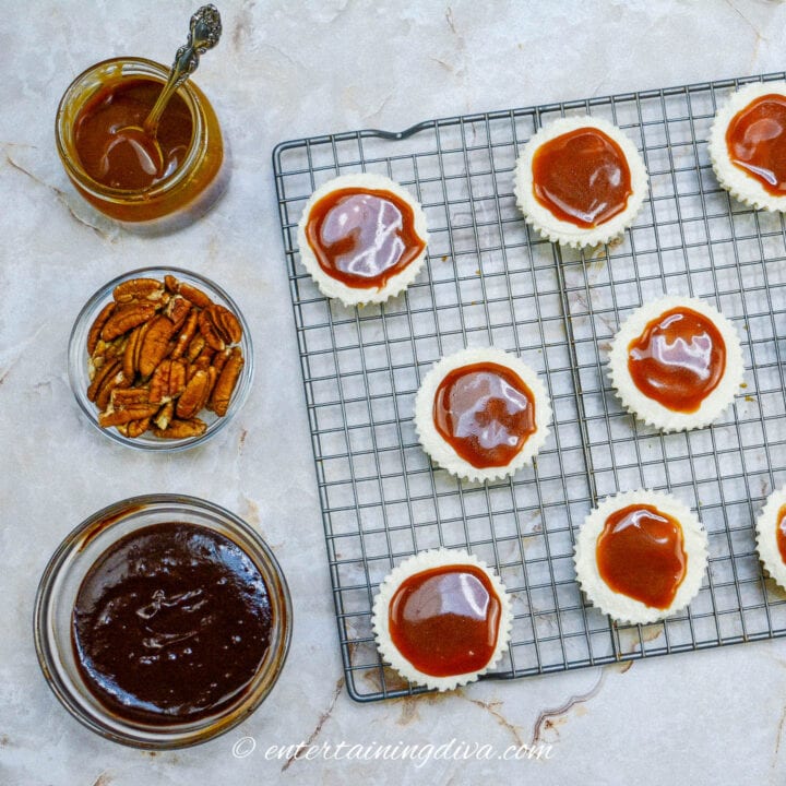 A rack of mini cheesecakes with caramel sauce on them.