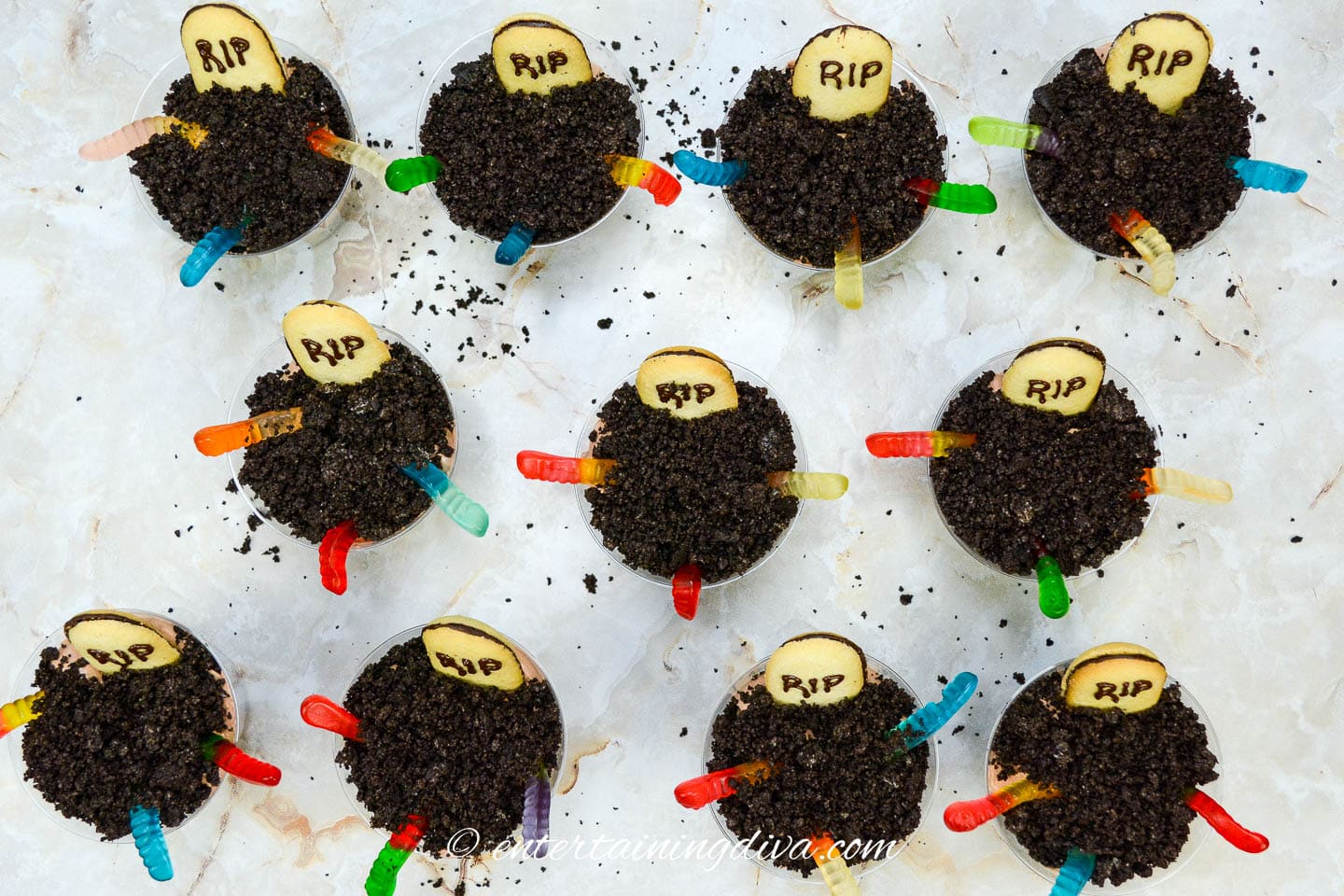 Halloween graveyard dirt pudding cups with cookie tombstones and gummy worms.