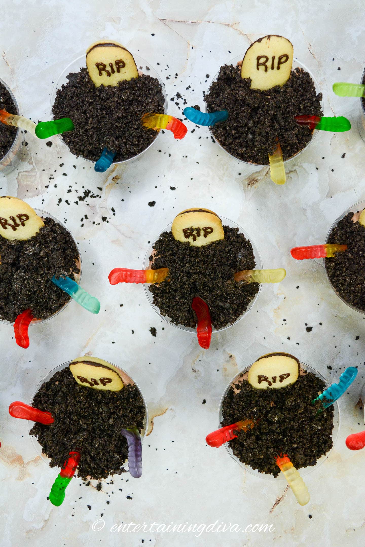 Halloween graveyard pudding cups decorated with gummy worms, tombstone cookies and Oreo cookie "dirt"