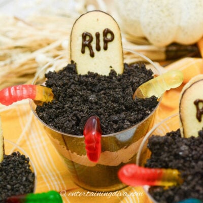 Halloween Graveyard Pudding Cups topped with Oreo cookie dirt, a tombstone cookie and gummy worms.