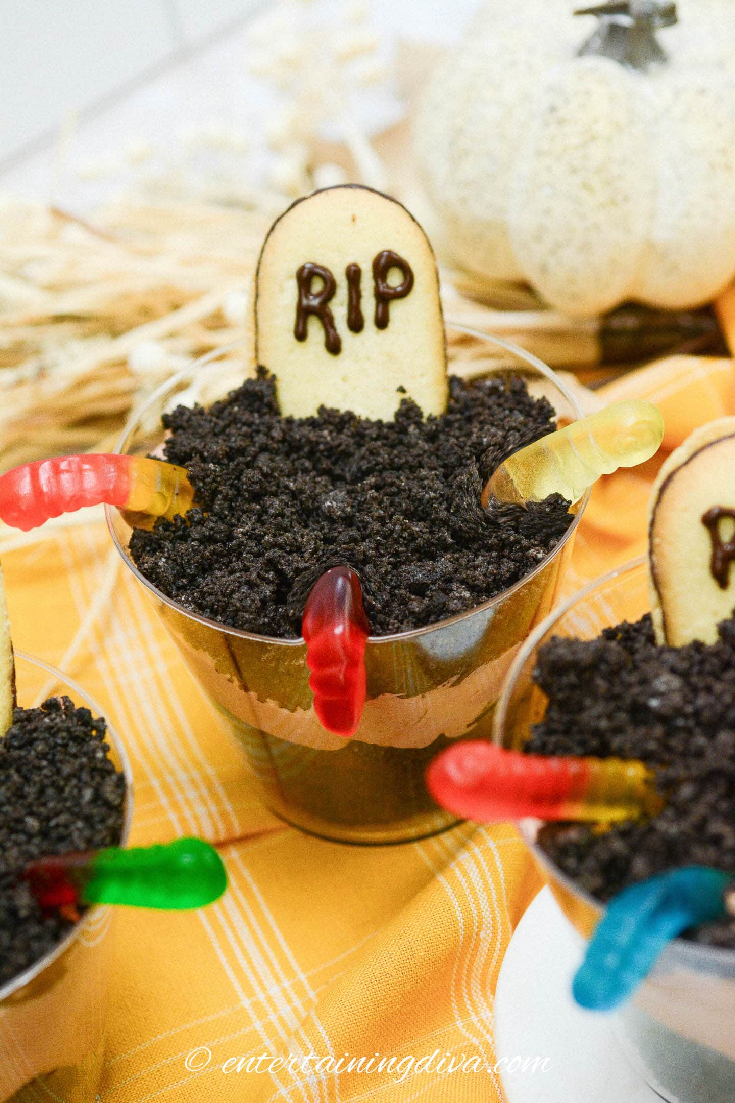 Halloween pudding cups decorated with tombstone cookies and gummy worms