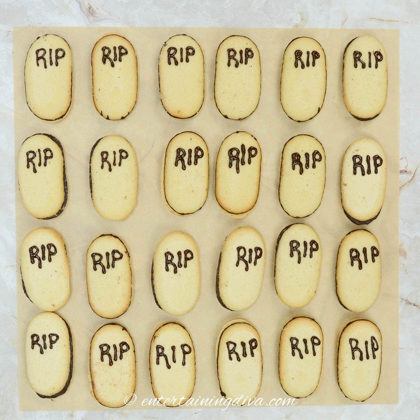 A tray of Halloween tombstone cookies with the word "rip" written on them.