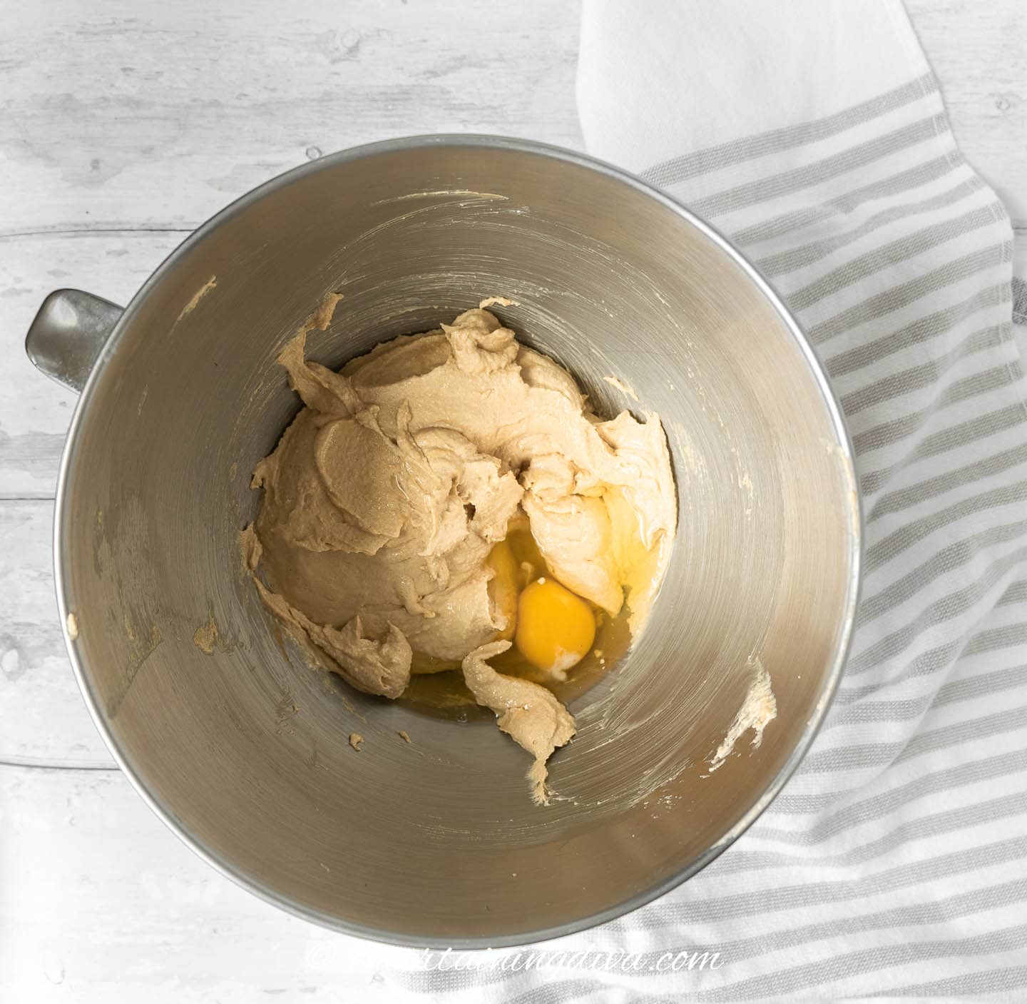 A mixing bowl filled with creamed butter, sugar, and peanut butter along with vanilla and an egg