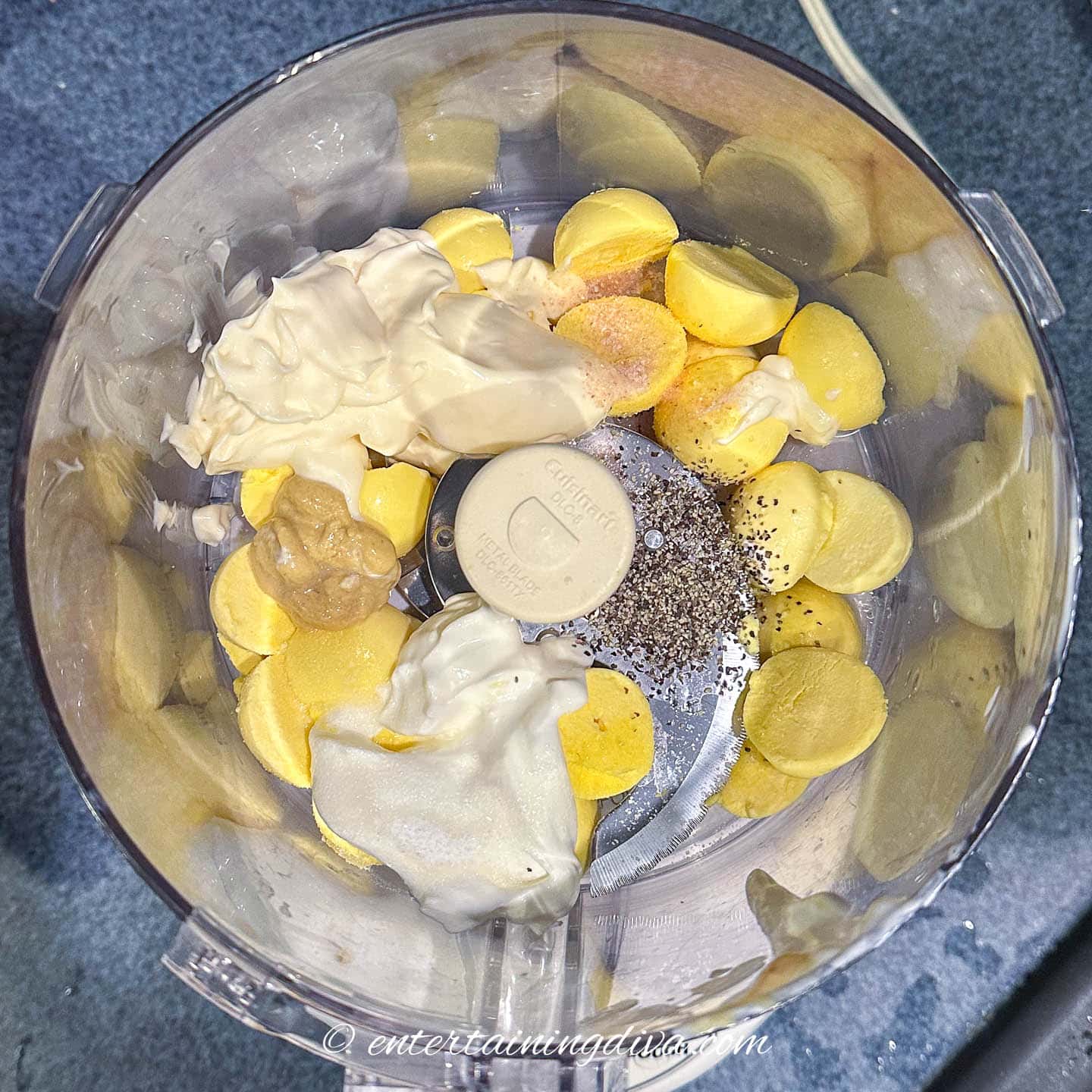 A food processor filled with the ingredients for classic deviled eggs.