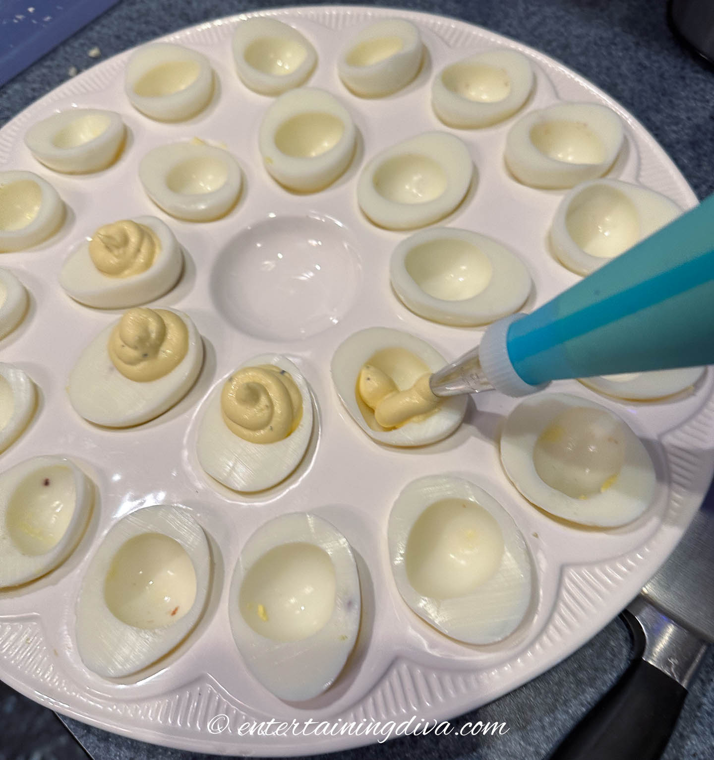 Deviled egg yolk mixture being piped into egg whites