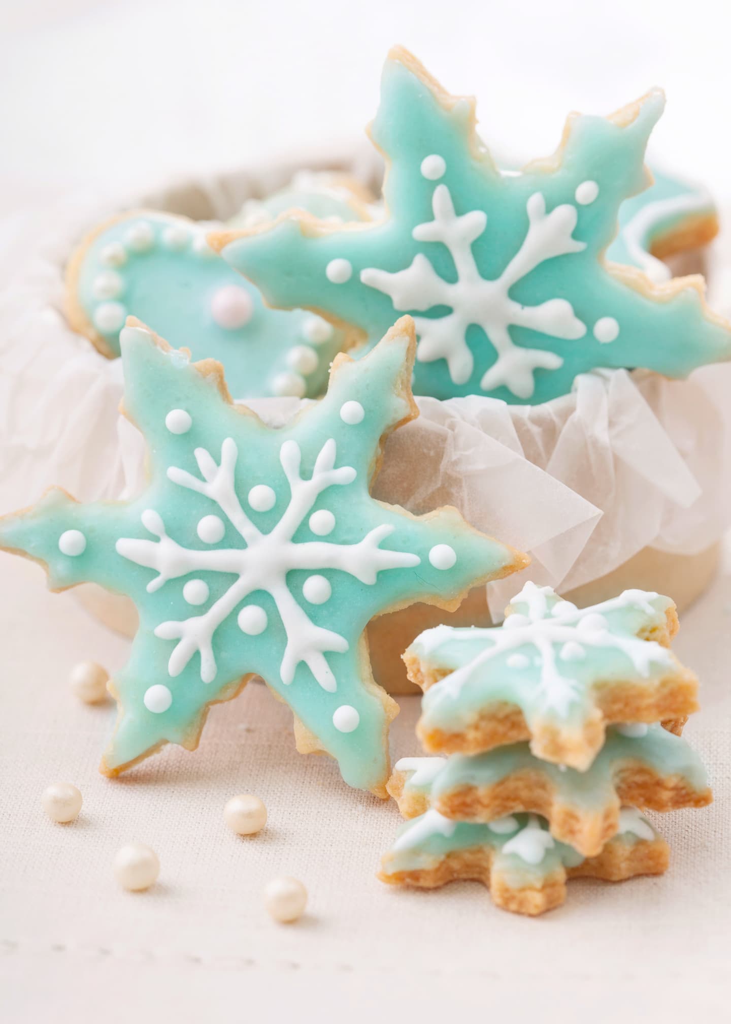 Snowflake sugar cookies flooded with light blue icing and lined with white icing.