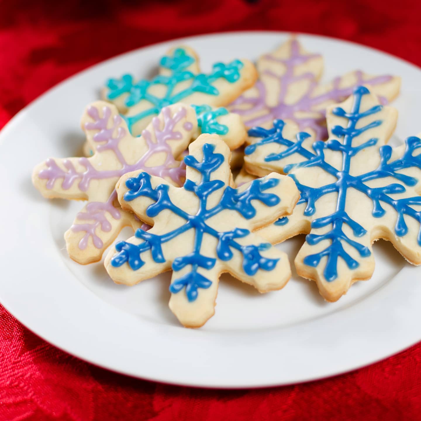 Snowflake sugar cookies with blue and pink royal icing lines drawn on them