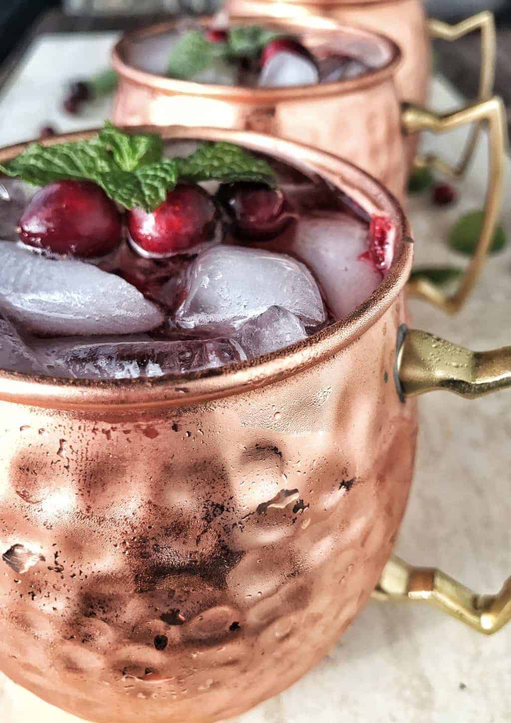 Cranberry spritzer in copper mugs with ice and mint.