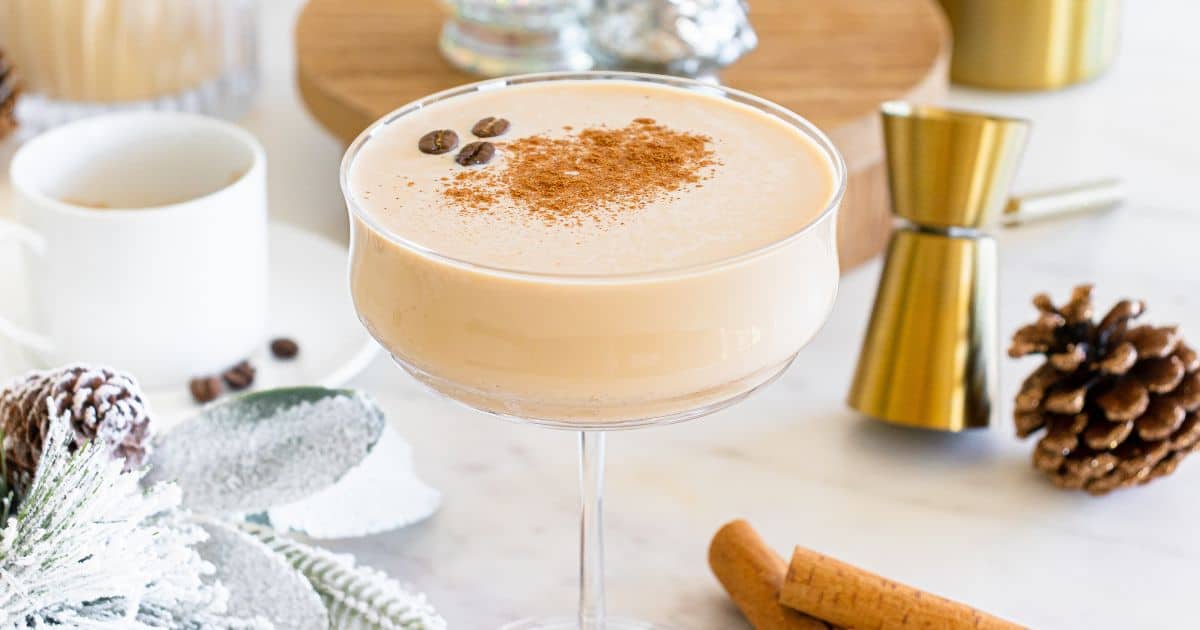 An eggnog espresso martini with cinnamon sticks and pine cones.