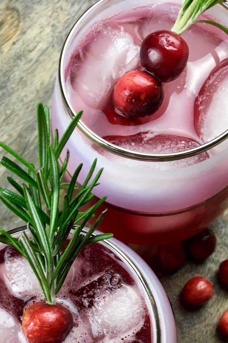 Two glasses of cranberry spritzer with rosemary sprigs.