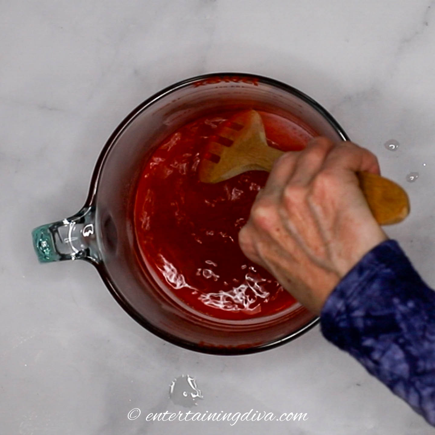 Hot water and jello being mixed in a bowl