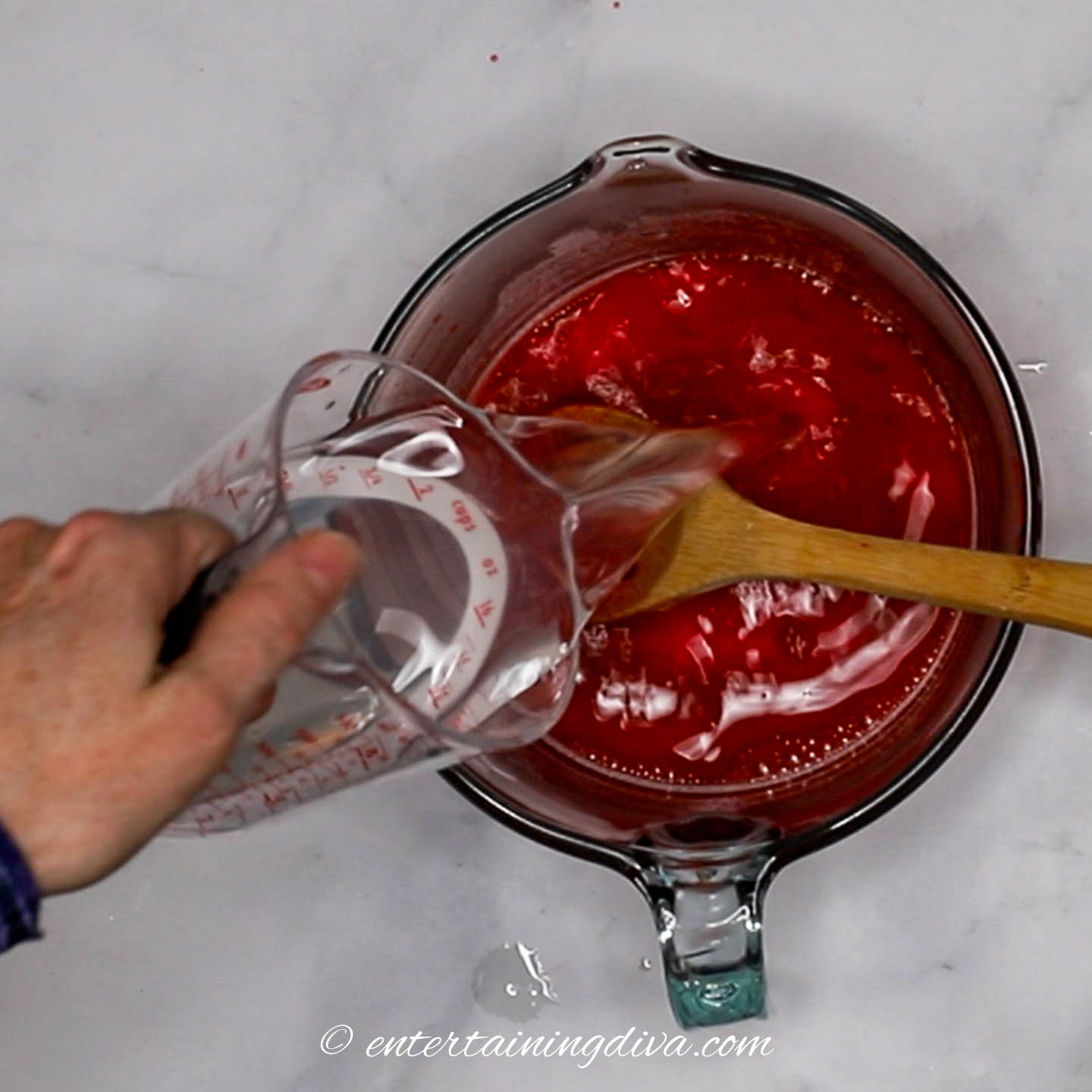 Vodka and lemonade being poured into gelatin mixture in a bowl