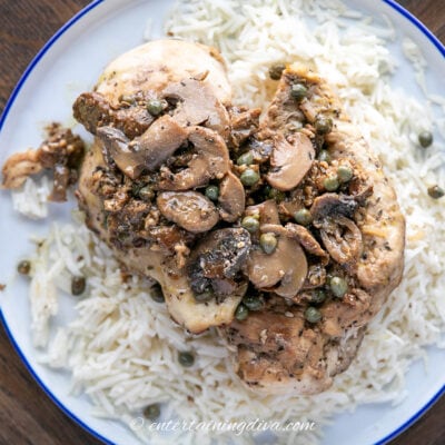 close up of chicken piccata with mushrooms on a plate of rice