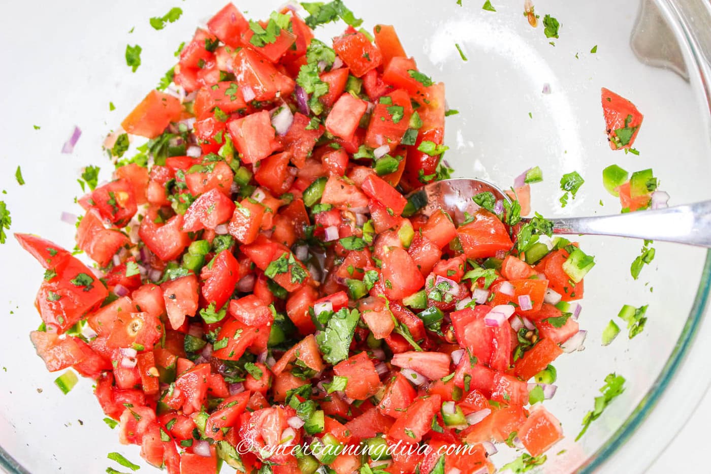 pico de gallo being mixed in a bowl