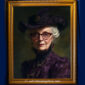 Victorian woman in a dark purple hat with feathers and matching dress, wearing glasses and layered jewelry, with a confident, mysterious expression.